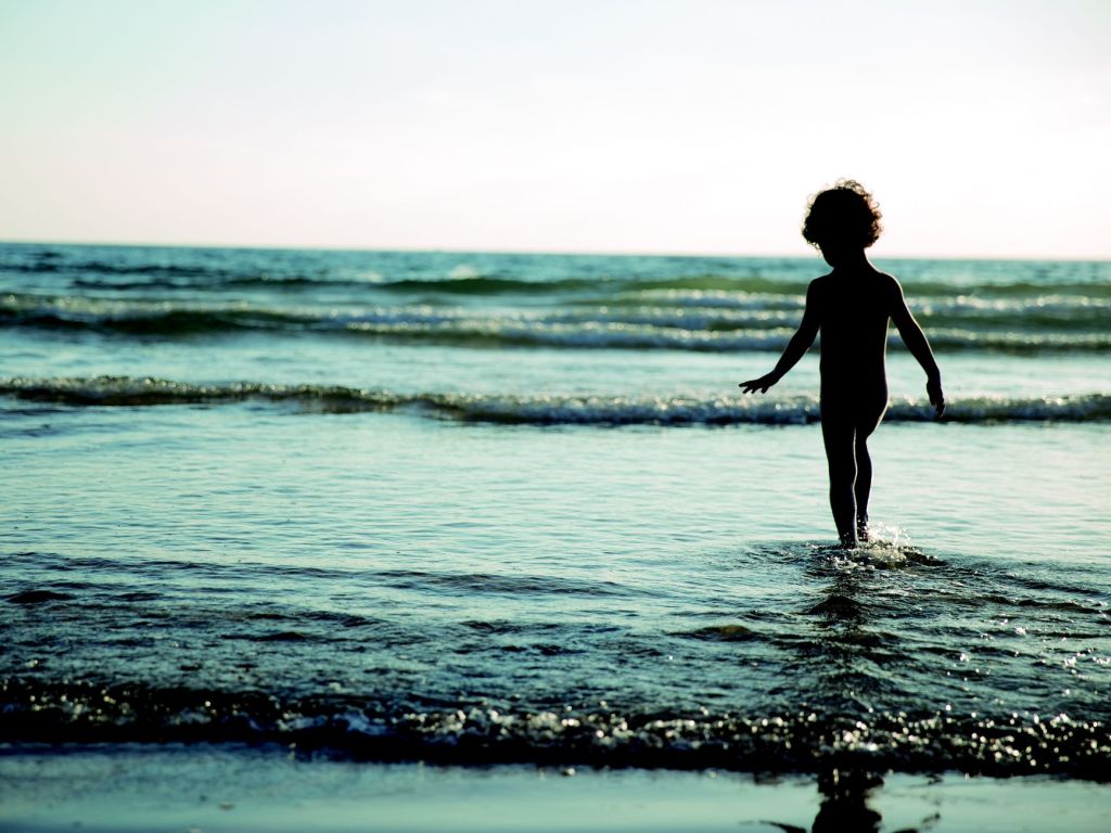 child walking on seashore during daytime