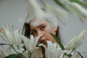 photo of a woman near white madonna lily flowers