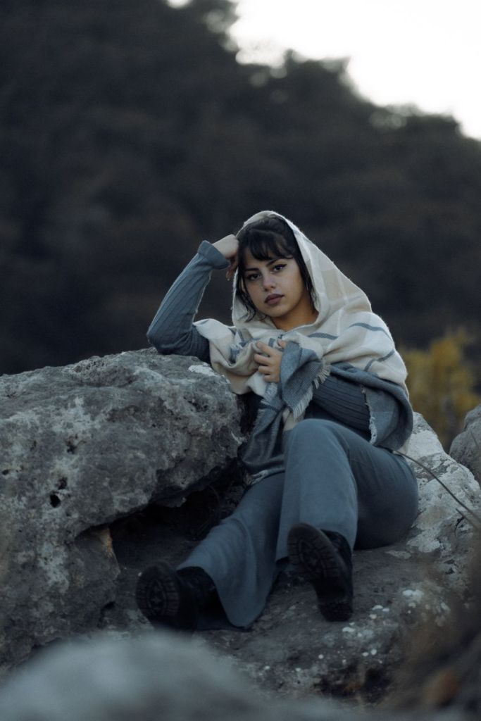 beautiful woman with a headscarf sitting on a rock in the mountains