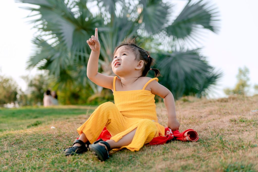 girl in yellow clothes sitting with finger raised