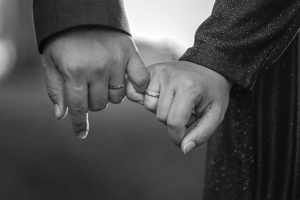 close up of couple holding hands with rings